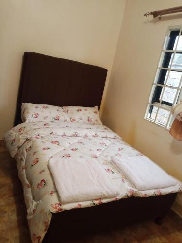 a bed with two blankets on it with a window at Kitale Heavenly Haven in Kitale