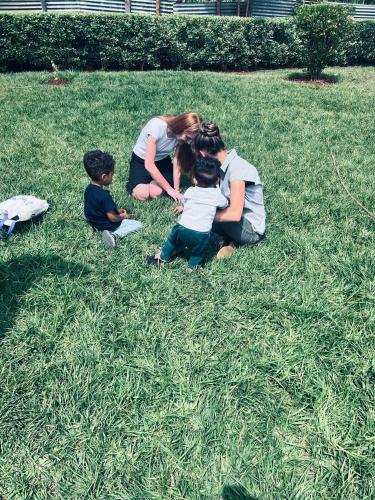 a woman and two children sitting in the grass at Kitale Heavenly Haven in Kitale