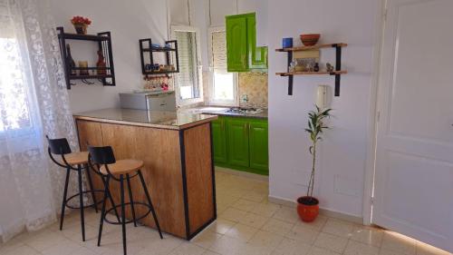 una cocina con armarios verdes y una barra con taburetes en Bensassi Urban Escape, en La Marsa