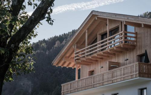 a wooden building with a balcony and a tree at Oberhemberger Hof in Feldthurns