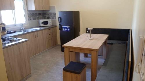 a kitchen with a wooden table and a black refrigerator at Room Breakfast in Zarzouna