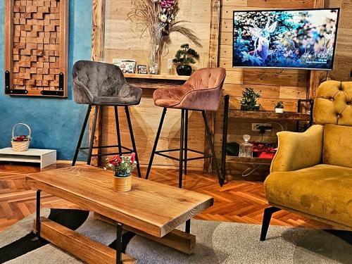 una sala de estar con dos taburetes de bar y una mesa en Center Lux Apartment Marijana, en Novi Sad