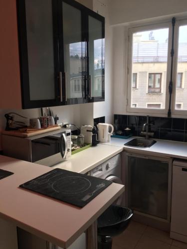 une cuisine avec des armoires noires et blanches et un évier dans l'établissement 2 pièces proche tour Eiffel, Trocadéro et OCDE, à Paris