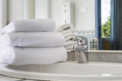 a stack of towels sitting on a bathroom sink at Hôtel & Résidence Avermes in Avermes