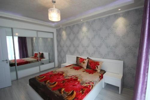 a bedroom with a bed with red flowers on it at Korallia Penthouse in Mamaia Nord