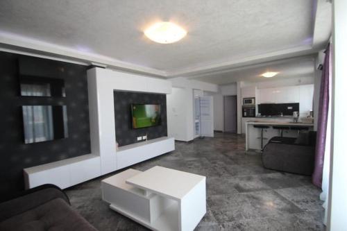 a living room with a couch and a tv at Korallia Penthouse in Mamaia Nord