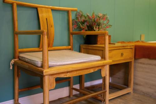 a wooden chair sitting next to a desk with a potted plant at Rong Hotel - Beijing Nanluoguxiang Branch in Beijing