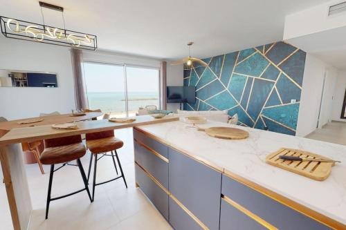 une cuisine avec un comptoir et une table avec des tabourets dans l'établissement Spendide appartement tout confort, Résidence Archipel T4 en bord de plage, avec grande terrasse aménagée,spa et parking privé, à Valras-Plage