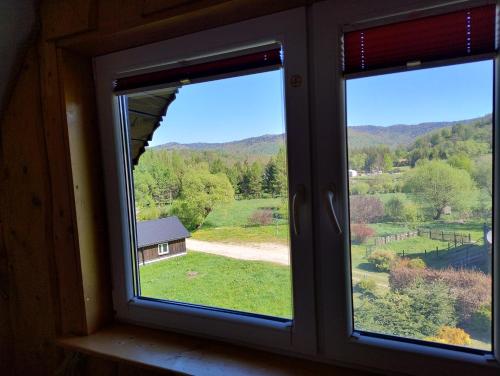 a window with a view of a house and a field at Podołynia in Dwernik