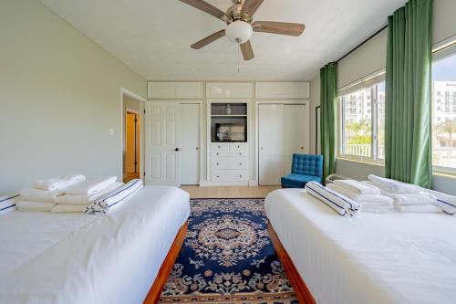 two beds in a room with a ceiling fan at Tropical Breeze in Clearwater Beach