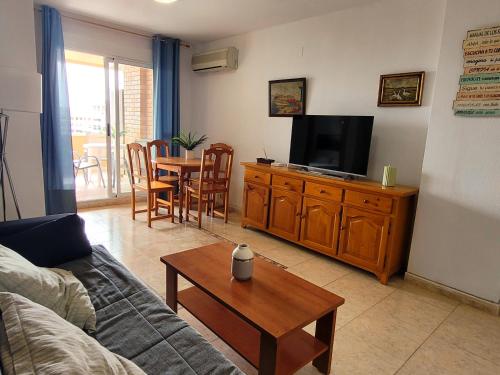 een woonkamer met een bank, een tv en een tafel bij Apartamento en 7ᵃ Planta - 1ᵃ Línea de Playa - Bahía Park, Marina d'Or in Oropesa del Mar