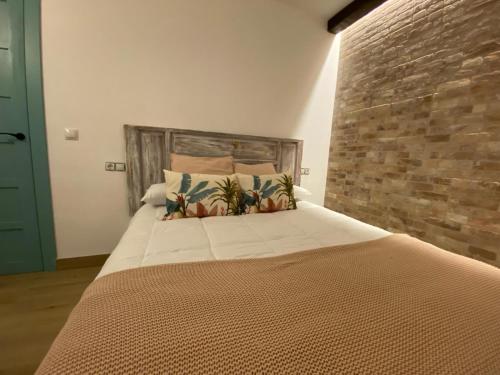 a large bed in a room with a brick wall at Apartamento Guadalvivir in Mogón