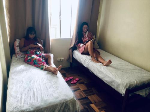 two women sitting on beds in a room at Vicz Palace Hotel in Curitiba