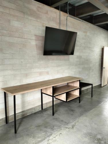 a wooden table with a tv on a brick wall at Hotel El Cordobes in Marinilla