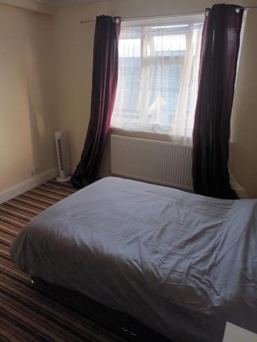 a bedroom with a bed and a window with curtains at Ansell road in London