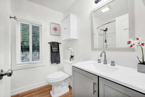 a white bathroom with a toilet and a sink at Retro Cottage, Hot Tub, Putting Green, walk to all in Thousand Oaks
