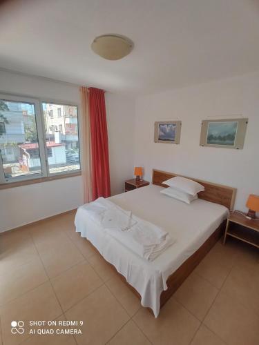a bedroom with a large white bed and a window at Guesthouse Kolevi in Lozenets
