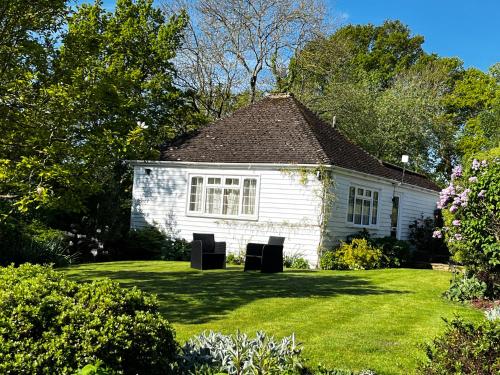 a white house with two black chairs in the yard at Huntleys Lodge in Ticehurst