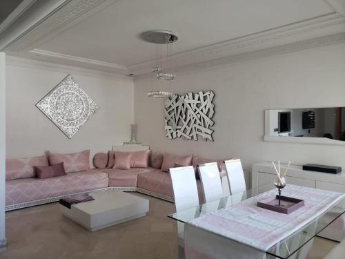ein Wohnzimmer mit einem rosa Sofa und einem Glastisch in der Unterkunft Luxurious apartment in Fès