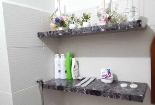 a shelf in a bathroom with bottles and flowers on it at Condotel at Mesavirre Bacolod City in Bacolod