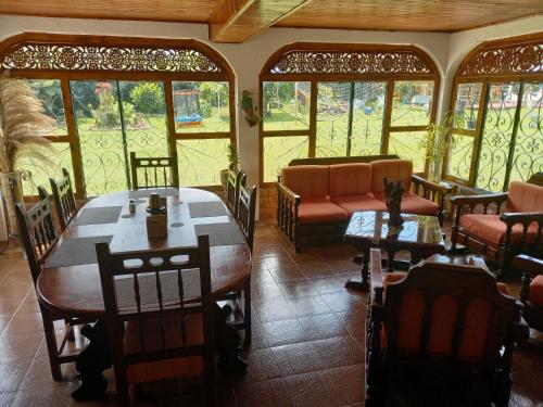 ein Esszimmer mit einem Tisch, Stühlen und Fenstern in der Unterkunft Alojamiento rural la pradera in Montenegro