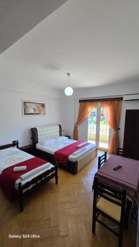 1 dormitorio con 2 camas, mesa y ventana en Vila Zeqo Muka, en Ksamil