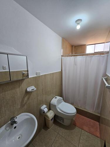 a bathroom with a white toilet and a sink at Hospedaje Las Parraz in Ica