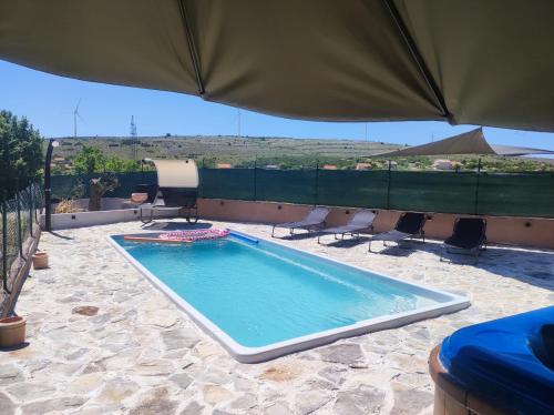 a swimming pool with chairs and an umbrella at Holiday House Mablo with pool & jacuzzi in Šibenik