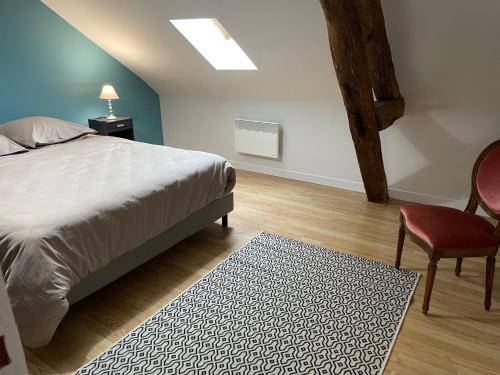 een slaapkamer met een bed, een stoel en een tapijt bij La Sauveroise in Saint-Sauveur-en-Puisaye