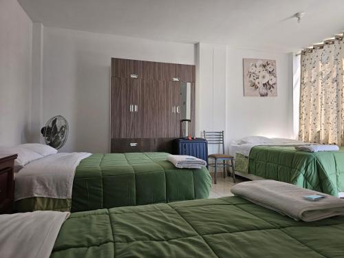 1 dormitorio con 2 camas con sábanas verdes en Hospedaje Las Parraz en Ica