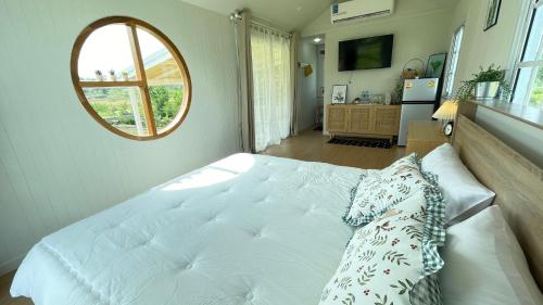 Schlafzimmer mit einem großen weißen Bett und einem Spiegel in der Unterkunft บ้านไร่ฟ้าสวยวังน้ำเขียว Little House in Ban Khlong Ta Sang