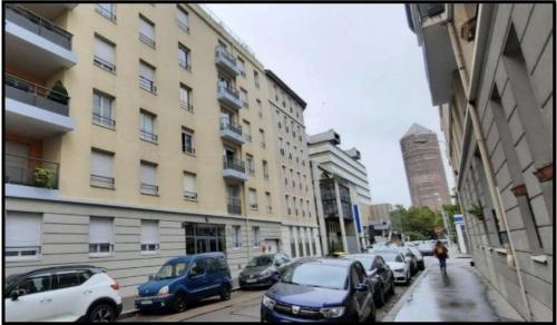 una calle de la ciudad con coches estacionados al lado de un edificio en Appartement part dieu en Lyon