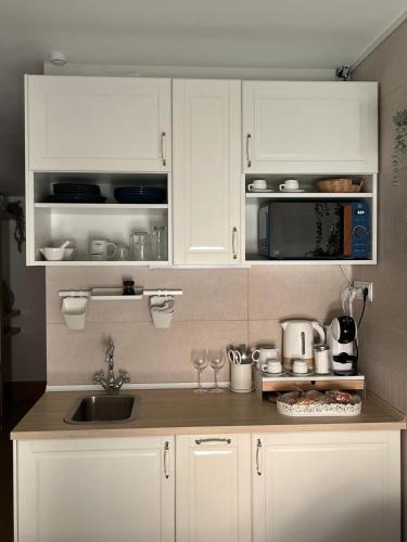 a kitchen with white cabinets and a sink and a microwave at GARDEN HOUSE Madrid in Madrid