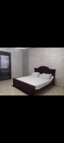 Bett mit weißer Bettwäsche und Kissen in einem Zimmer in der Unterkunft Résidence Abdel Rahman in Mostaganem