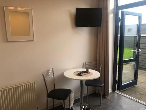 uma mesa branca e cadeiras num quarto com televisão em Motel eat´n drive Padborg em Padborg