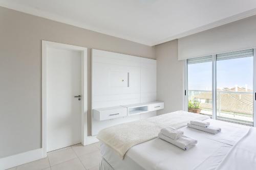 1 dormitorio blanco con 1 cama con 2 toallas en Cobertura Frente MAR no Santinho | Piscina #CSA03 en Florianópolis