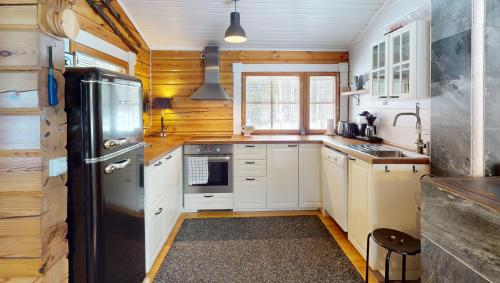 a kitchen with white cabinets and a black refrigerator at Levin Rankis in Kittilä