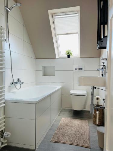 Baño blanco con bañera y lavamanos en OVERNIGHT Apartment No1 - Dachterrasse, Küche en Hannover