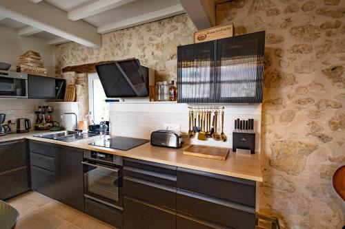 a kitchen with black cabinets and a counter top at Le Mas Gascon - Maison de vacances 4 étoiles avec piscine et vue proche de Lectoure in Marsolan