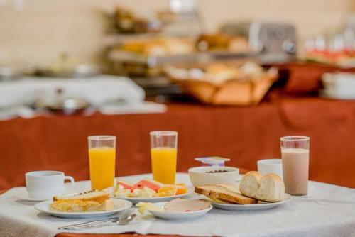 una mesa con platos de desayuno y dos vasos de zumo de naranja en HOTEL GAVINA EXPRESS IQUIQUE, en Iquique