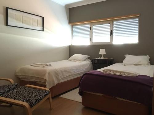 1 dormitorio con 2 camas, 1 silla y 2 ventanas en Caminho de Santiago, Alandroal, en Alandroal