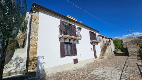a white building with two windows and a cobblestone street at Borgo Maria Rosa in San Salvatore di Fitalia