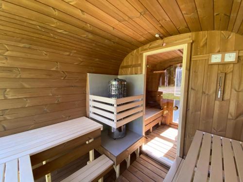 a wooden cabin with a bench and a stove in it at Alytaus Kempingas in Alytus
