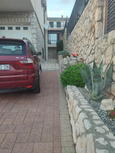 a red car parked next to a stone wall at Biuk Apartments in Novi Vinodolski