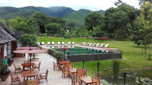 a resort with a pool with chairs and tables and umbrellas at Villa Inle Boutique Resort in Nyaung Shwe