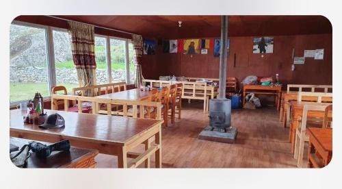 KhumjungにあるTrekkers Lodgeの木製のテーブルと椅子、薪ストーブのあるレストラン