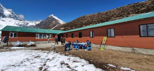 grupa ludzi siedzących przy stole przed budynkiem w obiekcie Trekkers Lodge w mieście Khumjung