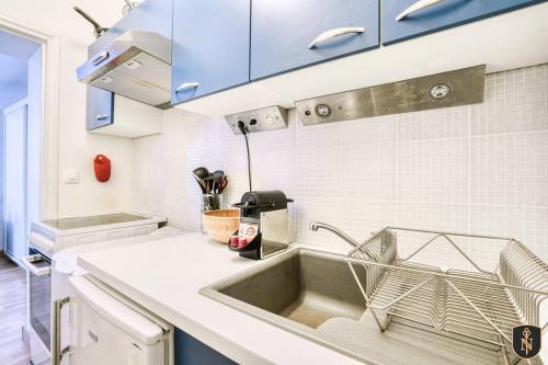 - une cuisine avec un évier et des placards bleus dans l'établissement Peaceful apartment in the heart of Caen, à Caen