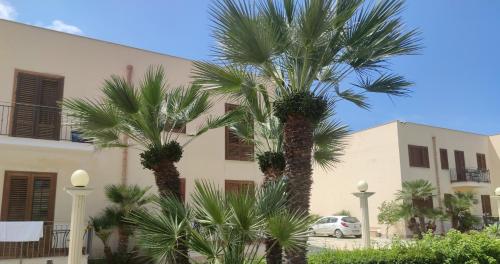 due palme di fronte a un edificio di holiday home LG a San Vito lo Capo