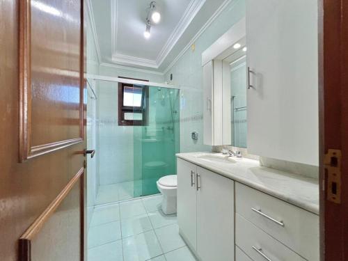 uma casa de banho com um WC e uma cabina de duche em vidro. em Quarto em Apartamento Amplo e Confortável em Caxias do Sul